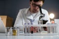 Scientist in lab coat and eyeglasses working at workplace with laptop in laboratory. Male doctor researcher are doing Royalty Free Stock Photo