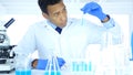 Scientist Looking at Test Tube blue Solution and using Microscope in Laboratory