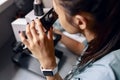 Scientist looks into microscope researching material sample at table in laboratory