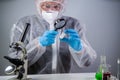 Scientist with magnifying glass. Covid-19 and the search for vaccine, chemist examines vial of coronavirus vaccine through