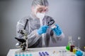 Scientist with magnifying glass. Covid-19 and the search for vaccine, chemist examines vial of coronavirus vaccine through