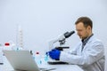 Scientist man doing chemical experiment, making analyzing, looking sample under microscope Royalty Free Stock Photo