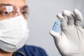 scientist man in goggles, gloves and a mask holds an ampoule of DNA, the concept of scientific molecular biotechnology, the study Royalty Free Stock Photo