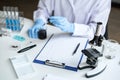 Scientist or medical in lab coat holding dropper with reagent, mixing reagents in glass flask, glassware containing chemical