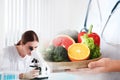 Scientist with microscope at table and her colleague. Food quality analysis Royalty Free Stock Photo