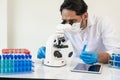 Scientist picks up sample tube of blue badger chemical along with analyzer in lab Technician holding test tubes Royalty Free Stock Photo