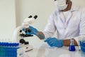 Scientist picks up sample tube of blue badger chemical along with analyzer in lab Technician holding test tubes Royalty Free Stock Photo