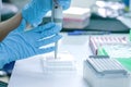 Scientist pipette dropping a sample into a test microtiter plate