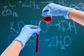 Scientist pouring liquid into test tube against chalkboard. Chemistry glassware Royalty Free Stock Photo