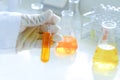 Scientist is preparation test tubes and orange liquid in flask in science laboratory Royalty Free Stock Photo