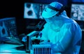 Scientist in protection suits and masks working in research lab using laboratory equipment: microscopes, test tubes