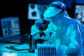 Scientist in protection suits and masks working in research lab using laboratory equipment: microscopes, test tubes