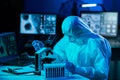 Scientist in protection suits and masks working in research lab using laboratory equipment: microscopes, test tubes