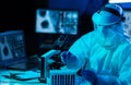 Scientist in protection suits and masks working in research lab using laboratory equipment: microscopes, test tubes