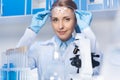 Scientist in protective gloves and glasses sitting at workplace in laboratory