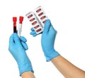 Scientist in protective gloves holding pills and test tubes of blood samples with label Covid-19 on white background, closeup Royalty Free Stock Photo