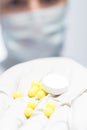 Scientist in protective suit holds pills in hand, close-up