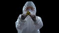 Scientist in protective suit showing ionizing radiation sign, black background