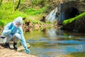 Scientist in protective suite taking water samples