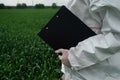 scientist in protective white PPE suit, treats seedlings, sprays leaves with fertilizers and fights infectious diseases, grows