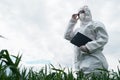 scientist in protective white PPE suit, treats seedlings, sprays leaves with fertilizers and fights infectious diseases, grows