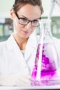 Scientist putting violet liquid into the flask