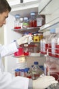 Scientist Selecting Bottle From Refrigerator