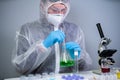 Scientist shaking green fluid in beaker. Young laboratory assistant making test or research in lab. Technician testing chemistry Royalty Free Stock Photo