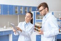 Scientist showing digital tablet to colleague holding test tubes Royalty Free Stock Photo