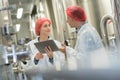 Scientist speaking to colleague holding clipboard in factory