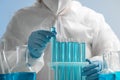 Scientist taking test tube with light blue liquid on grey background, closeup Royalty Free Stock Photo