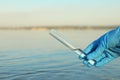 Scientist with test tube taking sample from river for analysis, closeup Royalty Free Stock Photo