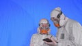 Scientist virologist in respirator makes write in an tablet computer with stylus. Man and woman wearing protective