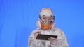 Scientist virologist in respirator makes write in an tablet computer with stylus. Woman wearing protective medical mask