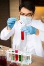 Scientist wear white coat and blue gloves holding dropper and drop red water to tube science. Chemist examines chemical test tube