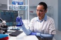 Scientist woman doctor holding glass flask analyzing liquid solution working at biochemistry experiment Royalty Free Stock Photo