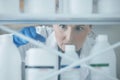 Scientist woman, shelf and bottle in lab with choice, thinking or idea for experiment, innovation or pharma career
