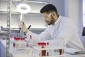 Serious young male scientist using a pipette while working in the pharma laboratory