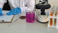 Scientist works in laboratory with microscope, test tubes, and colored liquid during a research process concept Royalty Free Stock Photo