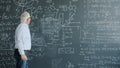Scientist writing formulas on chalkboard underlining equation teaching science in class