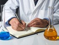 Scientist Writing Notes in Laboratory with Beakers and Test Tubes Royalty Free Stock Photo