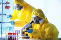 Scientists in chemical protective suits working. Virus research
