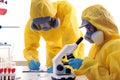 Scientists in chemical protective suits working. Virus research