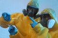 Scientists in chemical protective suits writing formula on glass board. Virus research