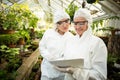 Scientists in clean suit looking at clipboard while examining plants Royalty Free Stock Photo