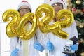 Scientists doctors holds numbers 2022 and microscope against background of New Year tree