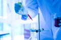 Scientists drop liquid into test tube in laboratory blue tone
