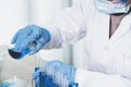 Scientists hand hold a glass filled with blue chemical liquid for research and analysis in a laboratory