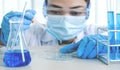 Scientists hold the pipette and drop the blue chemical liquid for research and analysis in a laboratory