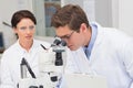 Scientists looking attentively in microscope